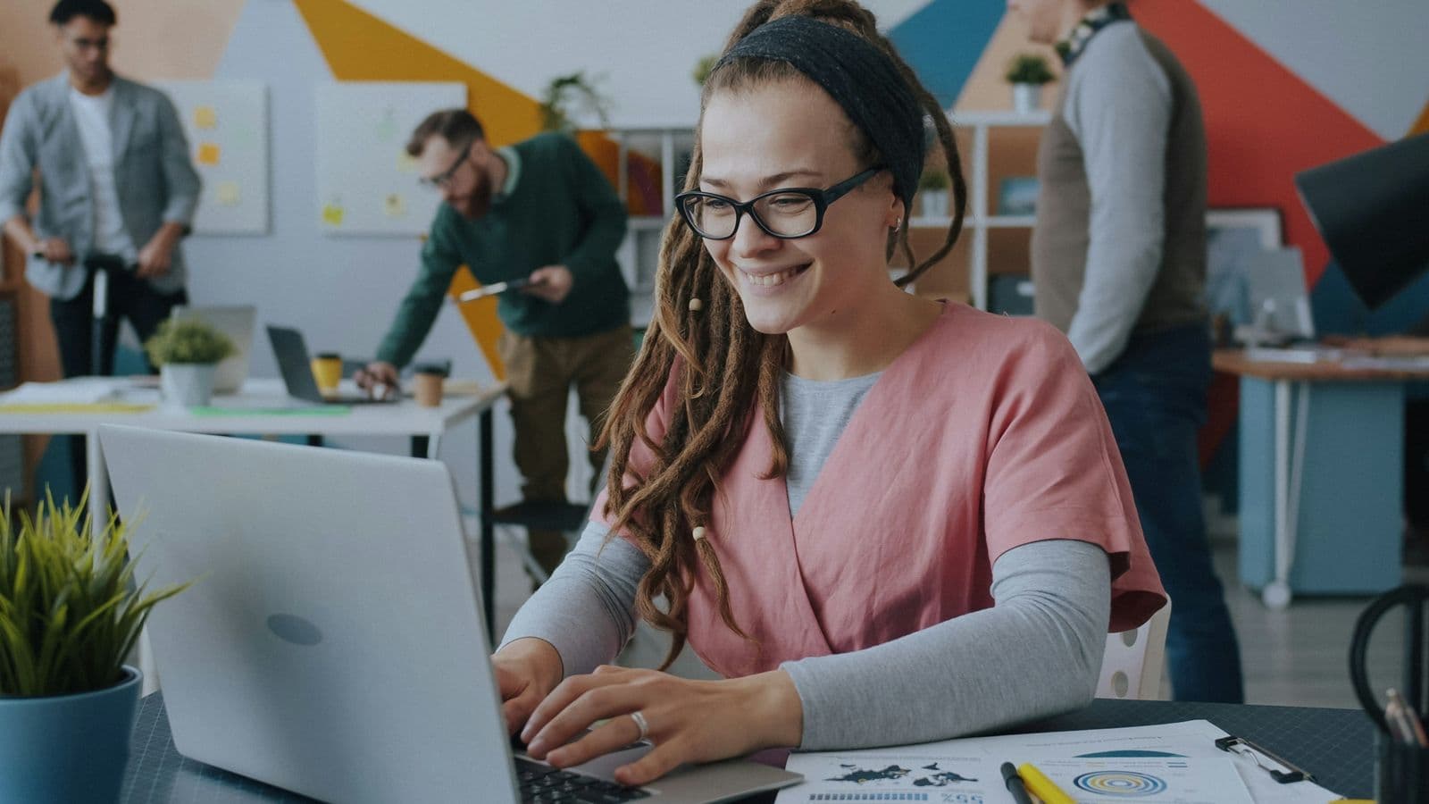 A smiling support team member working on her laptop in a busy office